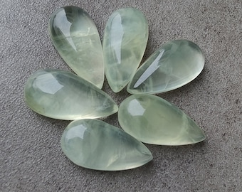 May include: Six teardrop-shaped green gemstones with a translucent, cloudy appearance.