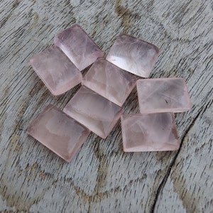 Peut inclure: Huit pierres de quartz rose rectangulaires rose pâle sur une surface en bois brun clair.