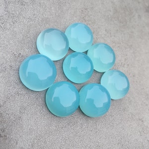 Pu&ograve; includere: Otto pietre preziose rotonde, lisce e di colore blu chiaro a cabochon. Le pietre sono disposte in cerchio su uno sfondo grigio.