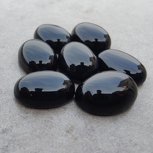 May include: Seven smooth, oval-shaped black gemstones. The stones are polished and have a glossy finish.