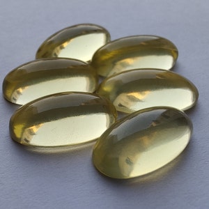 May include: Six oval-shaped, translucent yellow gemstones. The gemstones are smooth and polished, with a slight sheen.