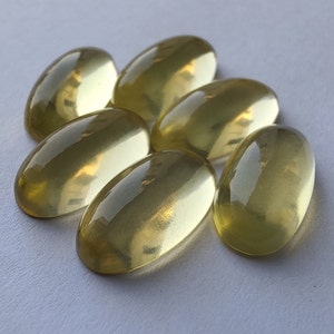May include: Seven oval-shaped, translucent yellow gemstones. The gemstones are smooth and polished, with a slight shimmer.