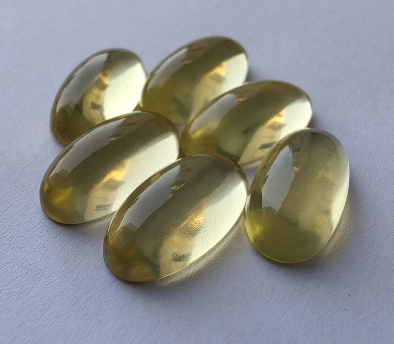 May include: Seven oval-shaped, translucent yellow gemstones. The gemstones are smooth and polished, with a slight shimmer.