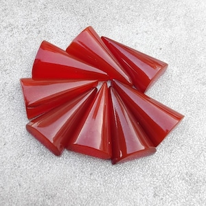 May include: A group of eight red carnelian gemstone points arranged in a circular pattern. The points are polished and have a smooth, glossy finish.
