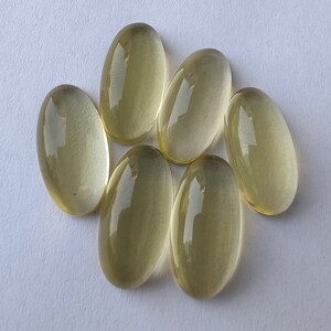 May include: Seven oval-shaped, translucent, light yellow gemstones. The gemstones are smooth and polished.