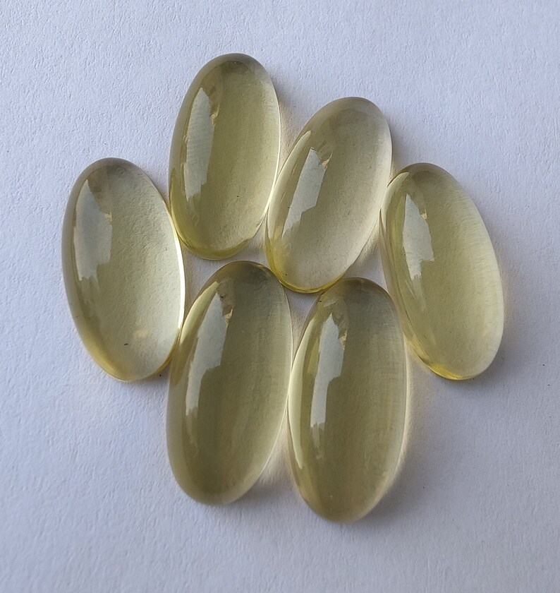 May include: Seven oval-shaped, translucent, light yellow gemstones. The gemstones are smooth and polished.