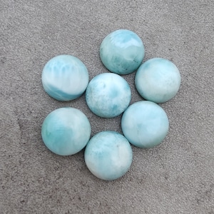 Puede incluir: Siete piedras preciosas redondas de cabujón azul claro con un patrón de mármol blanco.