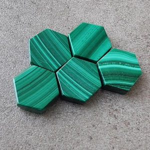 Puede incluir: Seis azulejos hexagonales de malaquita verde con un patrón de remolino.