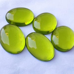 May include: Five oval-shaped green glass stones. The stones are smooth and shiny.