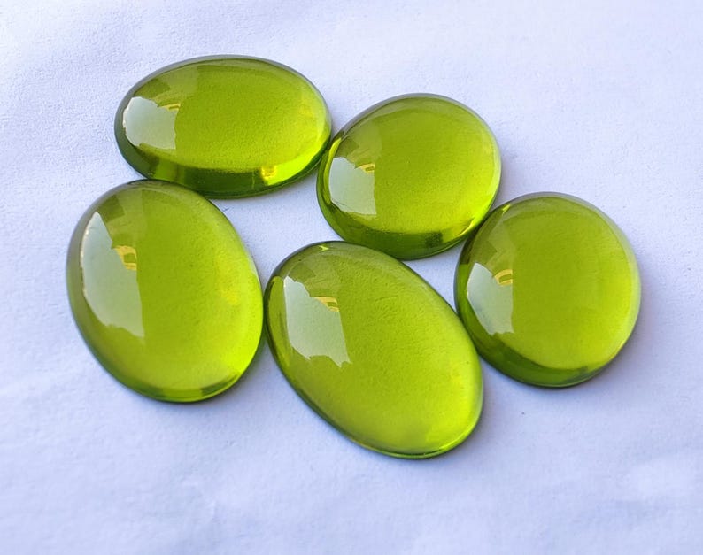 May include: Five oval-shaped green glass stones. The stones are smooth and shiny.