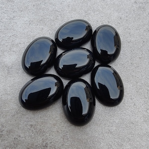 May include: Seven smooth, black oval-shaped stones. The stones are polished and have a glossy finish.