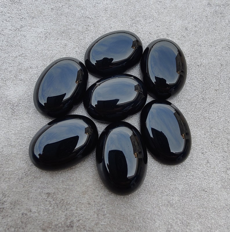 May include: Seven smooth, black oval-shaped stones. The stones are polished and have a glossy finish.