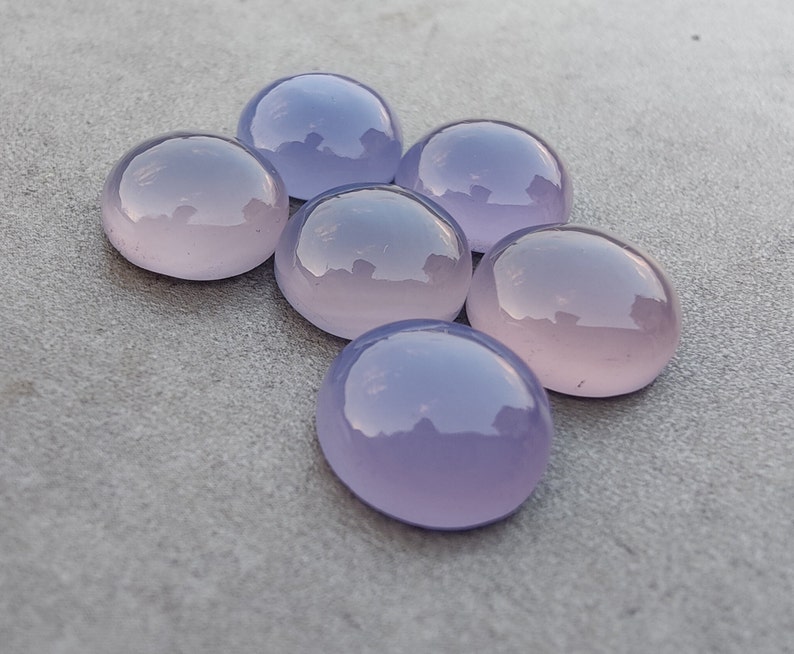 以下が含まれることがあります： 6つの丸い、滑らかな、ラベンダー色の宝石。宝石は半円形に配置されています。