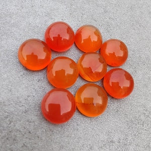 May include: Ten round, orange carnelian gemstones. The gemstones are smooth and polished.