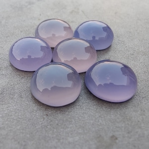 以下が含まれることがあります： 6つの滑らかで丸い、紫とピンクのカルセドニーのカボション。石は研磨されており、半透明な外観をしています。