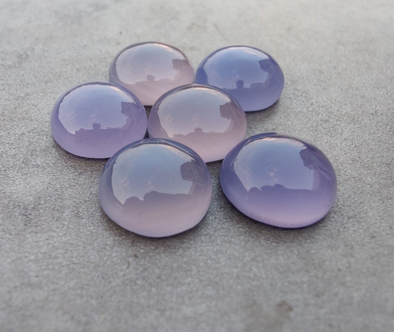 以下が含まれることがあります： 6つの滑らかで丸い、紫とピンクのカルセドニーのカボション。石は研磨されており、半透明な外観をしています。