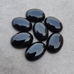 May include: Seven smooth, oval-shaped black gemstones. The stones are polished and have a glossy finish.