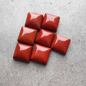 May include: Eight square-shaped red gemstone cabochons, arranged in a staggered pattern.