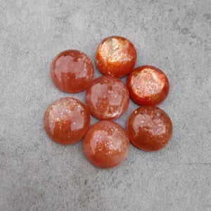 May include: Seven round, orange sunstone cabochons with a sparkly, iridescent finish.