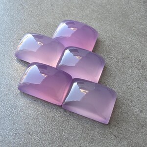 Pu&ograve; includere: Cinque pietre preziose rettangolari lucide in varie tonalit&agrave; di lavanda e viola. Le pietre hanno una parte superiore arrotondata e una finitura lucida, che riflette la luce. Le pietre sono disposte in modo leggermente sovrapposto.