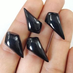 May include: Four black gemstone cabochons in a pointed, teardrop shape. The gemstones are polished and have a glossy finish.