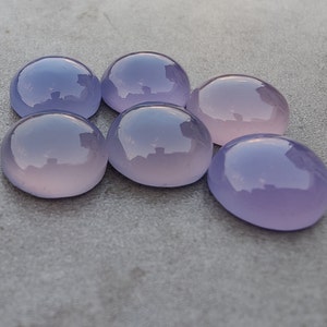 以下が含まれることがあります： 6つの滑らかで丸い、紫とピンクのcabochon宝石。石は磨かれており、半透明な外観をしています。