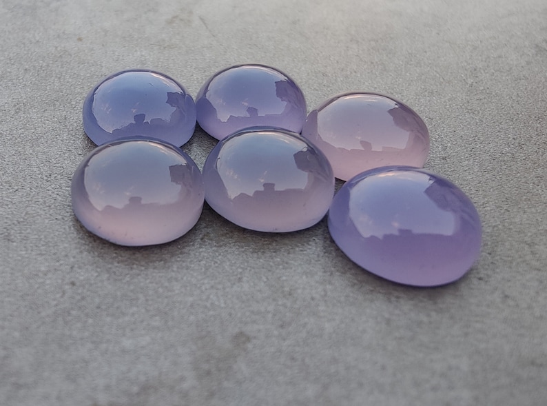 以下が含まれることがあります： 6つの滑らかで丸い、紫とピンクのcabochon宝石。石は磨かれており、半透明な外観をしています。