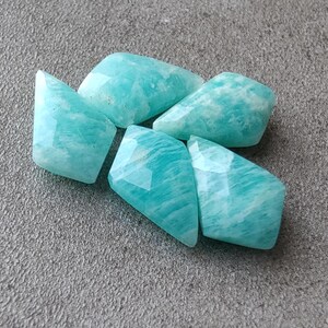 May include: Five faceted, light blue, green, and white amazonite gemstone beads. The beads are irregularly shaped and have a smooth, polished finish.