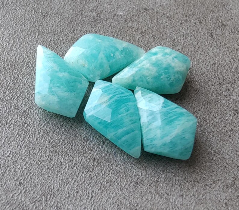 May include: Five faceted, light blue, green, and white amazonite gemstone beads. The beads are irregularly shaped and have a smooth, polished finish.