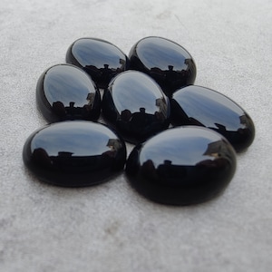 May include: Seven smooth, oval-shaped black gemstones. The stones are polished and have a glossy finish.