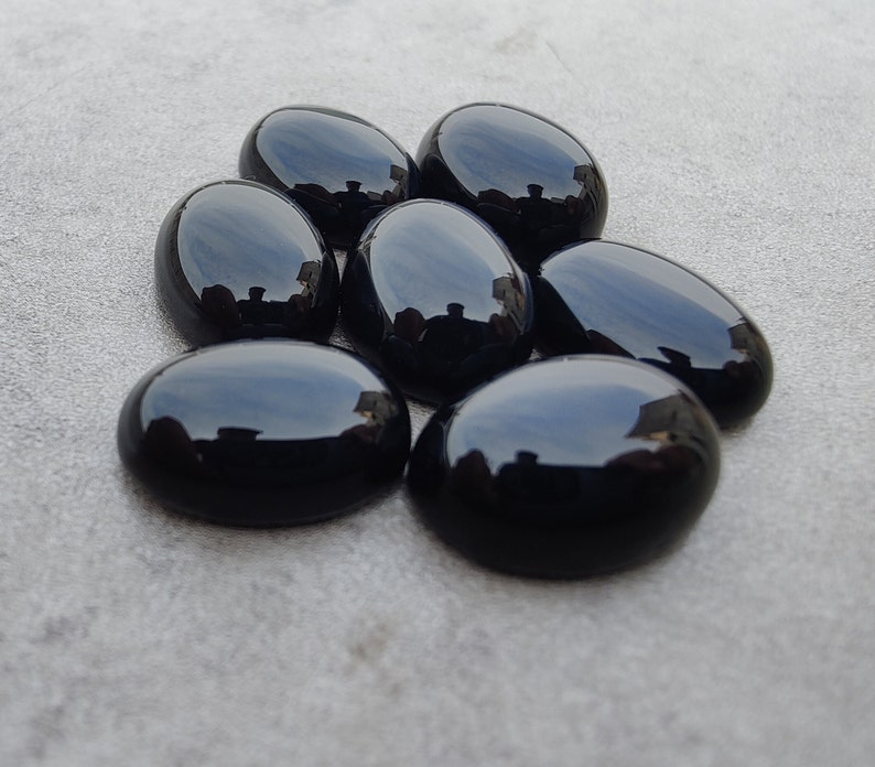 May include: Seven smooth, oval-shaped black gemstones. The stones are polished and have a glossy finish.