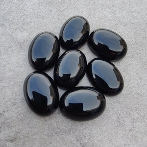 May include: Seven smooth, black oval-shaped gemstones. The stones are polished and have a glossy finish.