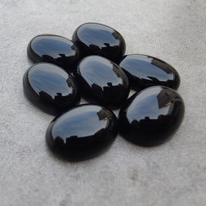 May include: Seven smooth, oval-shaped black gemstones. The stones are polished and have a glossy finish.
