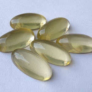 May include: Six oval-shaped, translucent yellow gemstones. The gemstones are smooth and polished, with a slight sheen.