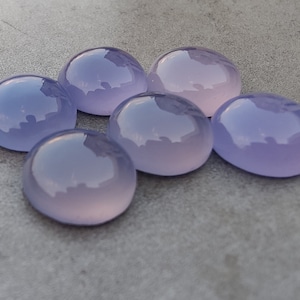 以下が含まれることがあります： 6つの丸い、滑らかな、ラベンダー色のカボションカットの宝石。石は研磨されており、半透明な外観をしています。