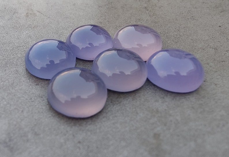 以下が含まれることがあります： 6つの丸い、滑らかな、ラベンダー色のカボションカットの宝石。石は研磨されており、半透明な外観をしています。
