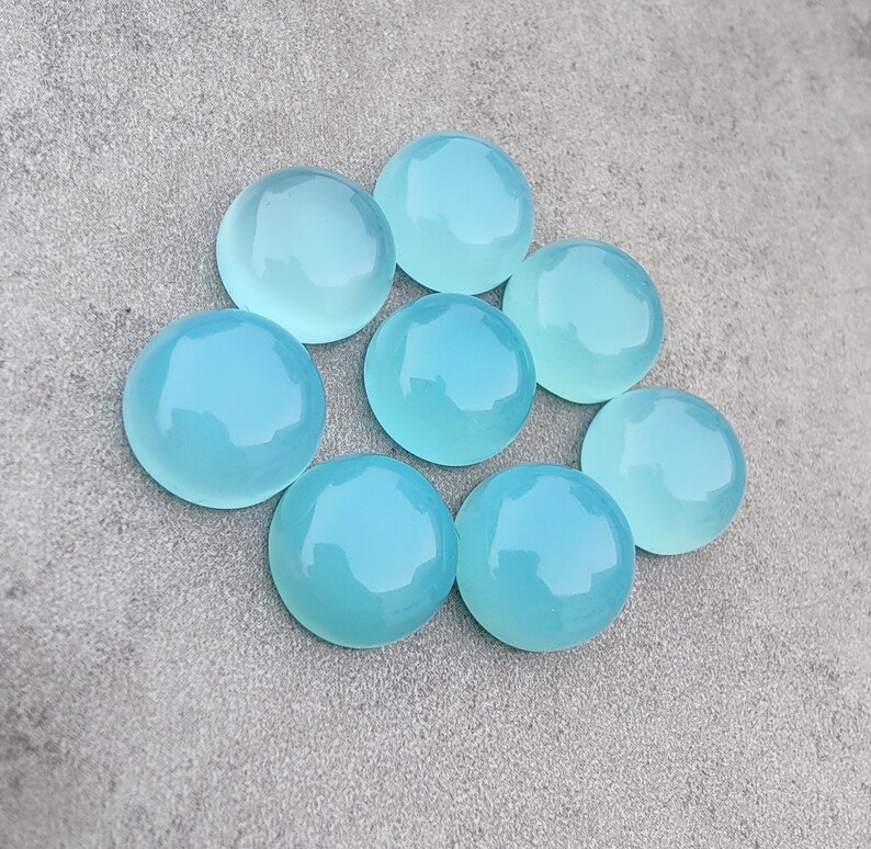 Pu&ograve; includere: Otto pietre preziose rotonde di cabochon blu chiaro. Le pietre preziose sono lisce e lucidate, con un leggero bagliore.