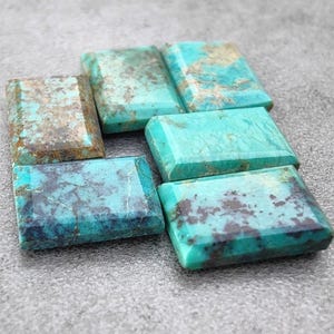 Puede incluir: Seis cabujones de turquesa en varios tonos de azul y verde con inclusiones marrones y negras. Los cabujones son rectangulares y tienen una superficie lisa y pulida.