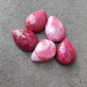 Puede incluir: Cinco piedras en forma de lágrima de color rosa y blanco. Las piedras son lisas y pulidas.