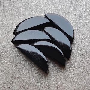 Può includere: Un gruppo di sei piastrelle in ceramica nere a forma di semicerchio. Le piastrelle sono disposte a ventaglio, con le punte dei semicerchi rivolte verso l'interno.