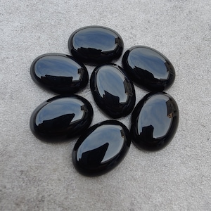 May include: Seven smooth, oval-shaped black gemstones. The stones are polished and have a glossy finish.