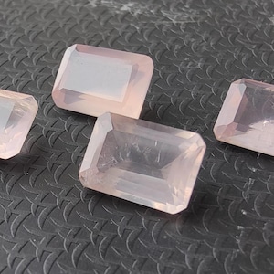 May include: Four pink, rectangular, faceted gemstones. The gemstones are translucent and have a light pink hue.