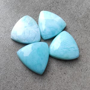 Puede incluir: Cuatro cabujones de piedra preciosa triangulares azules y blancos. Los cabujones están dispuestos en forma de flor.