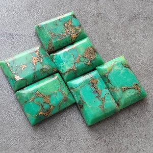 May include: Six green and gold turquoise cabochons, cut in a rectangular shape. The stones have a mottled pattern of green and gold.