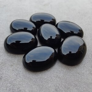 May include: Seven smooth, oval-shaped black gemstones. The stones are polished and have a glossy finish.