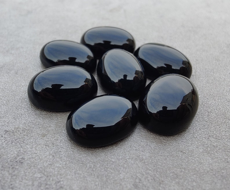 May include: Seven smooth, oval-shaped black gemstones. The stones are polished and have a glossy finish.