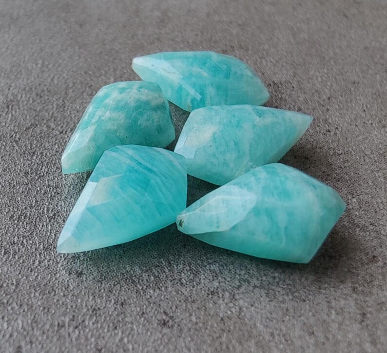 May include: Five teal blue, faceted, teardrop-shaped amazonite gemstones.