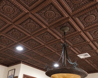 May include: A ceiling covered in square copper-colored tiles featuring an embossed floral and geometric pattern. A large hanging chandelier with a bowl-shaped amber glass shade and dark metal frame is suspended from the center of the ceiling.