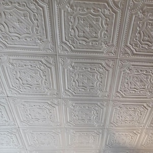 May include: White ceiling tiles with a decorative embossed pattern. The tiles are arranged in a grid pattern.