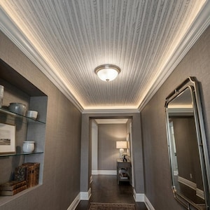 May include: A hallway with a light fixture and a decorative ceiling. The ceiling is made of light-colored wood panels. The walls are a neutral gray color. A mirror hangs on the right wall, and a shelf with decor is on the left.